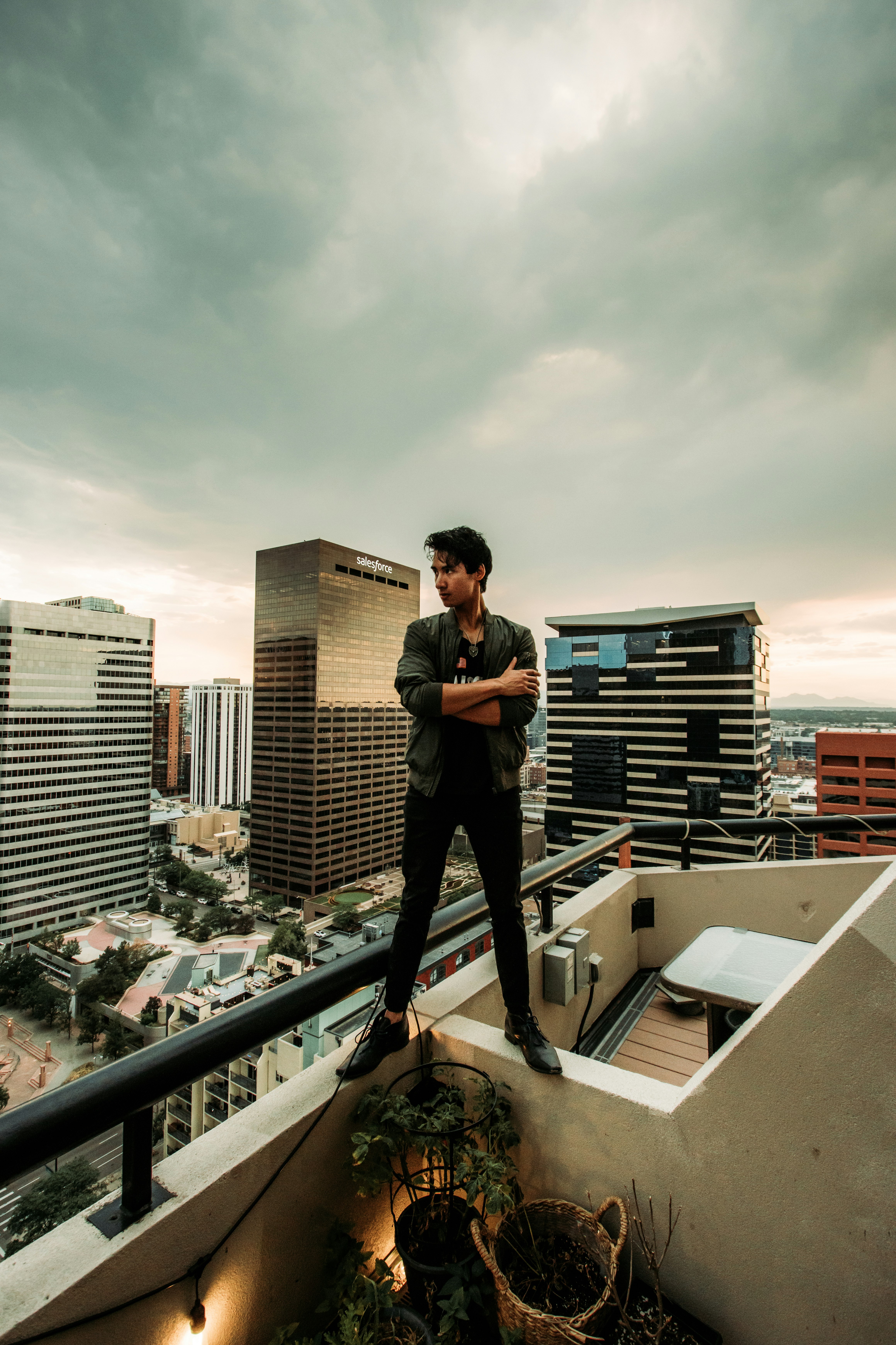 man in black jacket and black pants standing on top of building during daytime